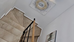 A staircase with a wooden handrail, a light fixture on the wall, and a framed artwork. - Charming 2-bedroom chalet with AC, WiFi in wonderful Málaga (AN)