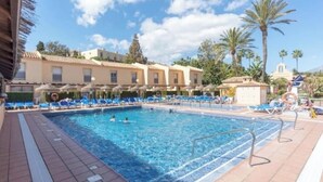 A swimming pool with blue lounge chairs and a tiled deck. - Charming 2-bedroom chalet with AC, WiFi in wonderful Málaga (AN)