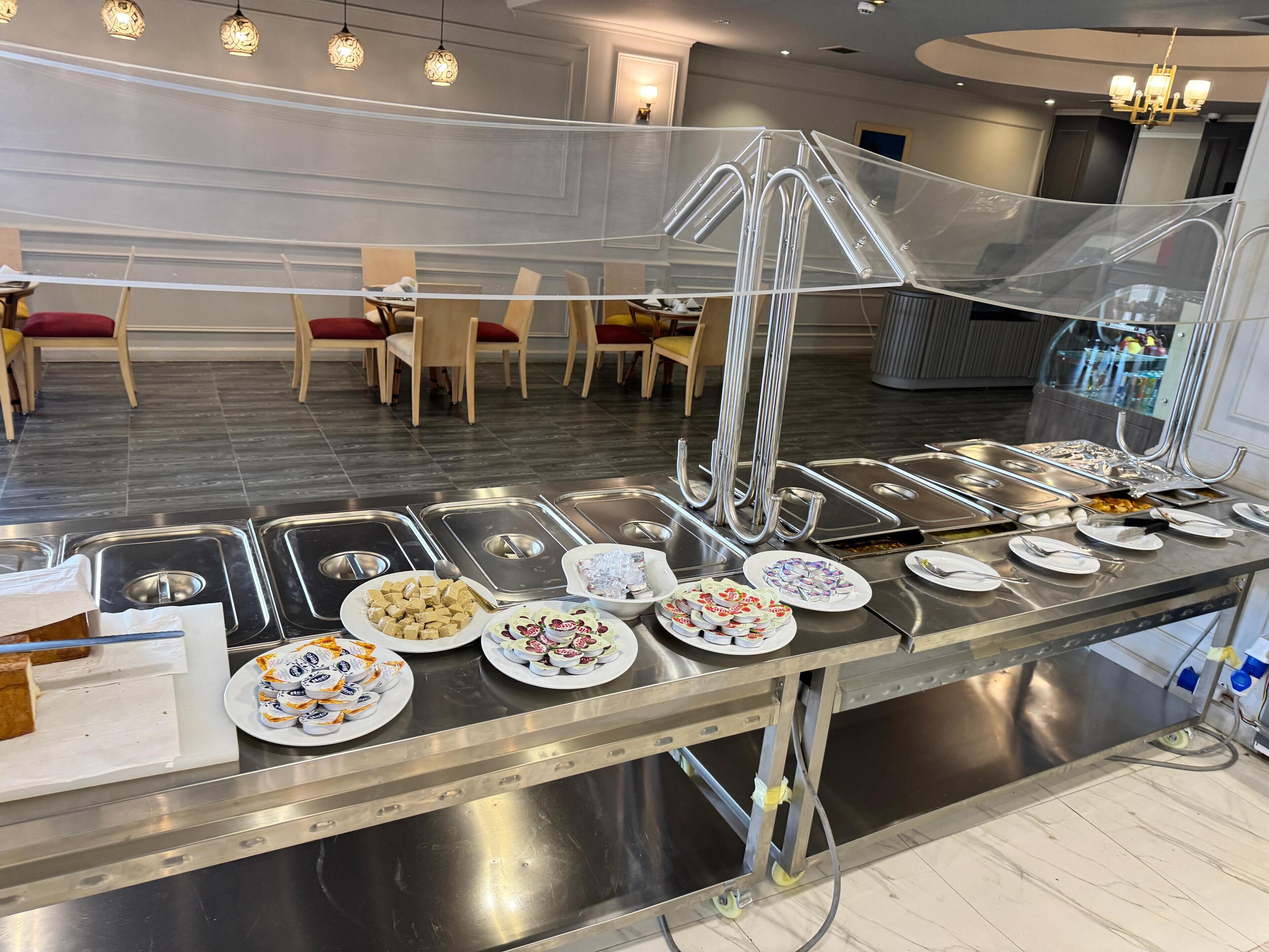 Montaje tipo bufé con varias estaciones de comida y asientos al fondo.