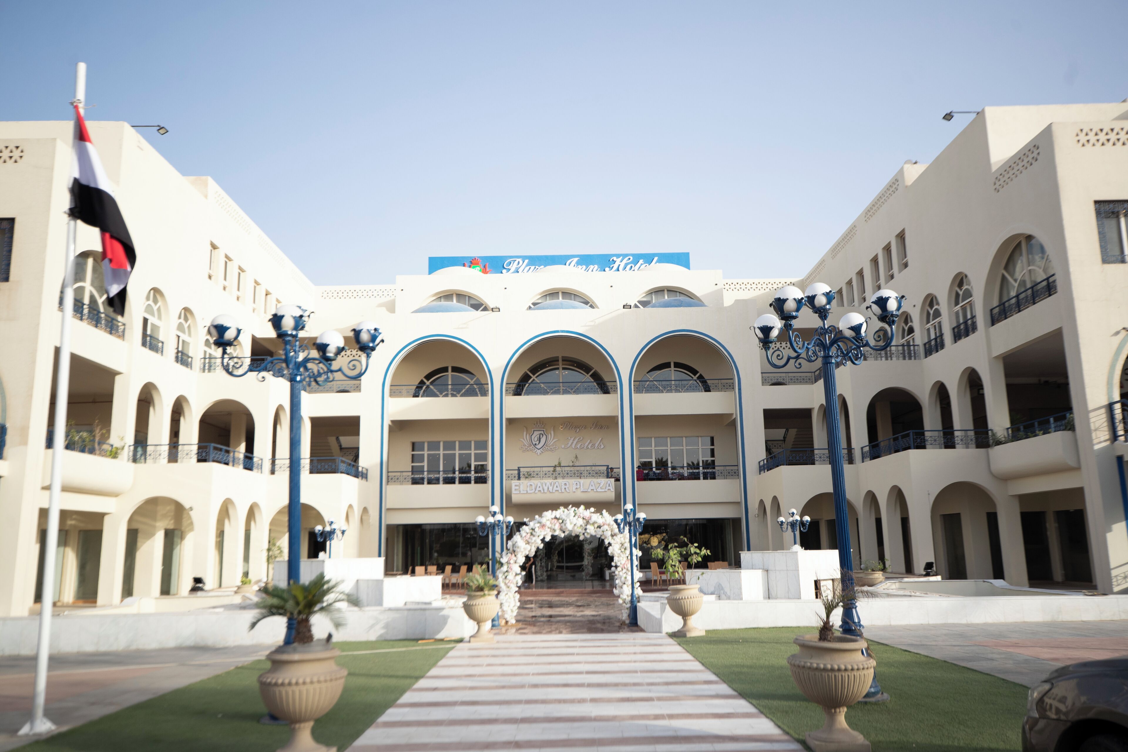 A hotel entrance with a central archway, multiple balconies, and a clear sky.