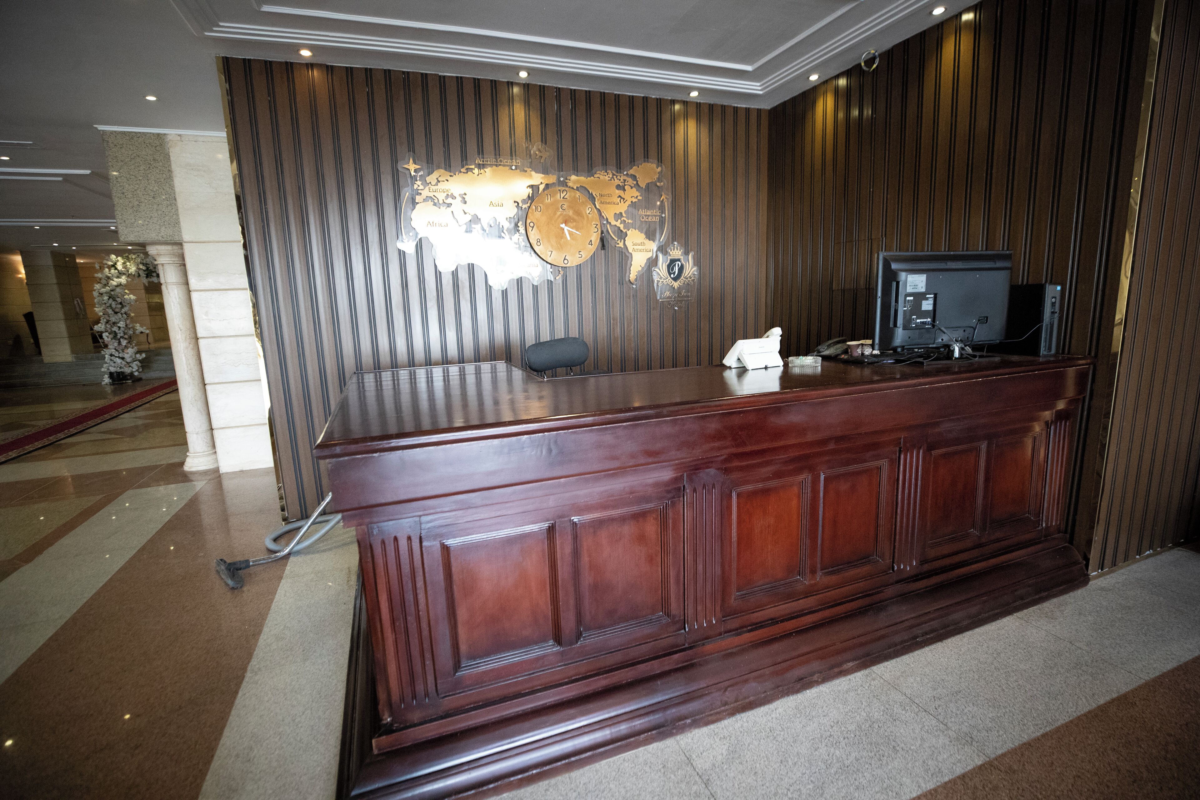 A reception desk with a world map, a clock, and a television.