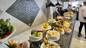 A buffet with various dishes, a brick wall, and hanging pendant lights. - oriental grand plaza (Tenth of Ramadan City)