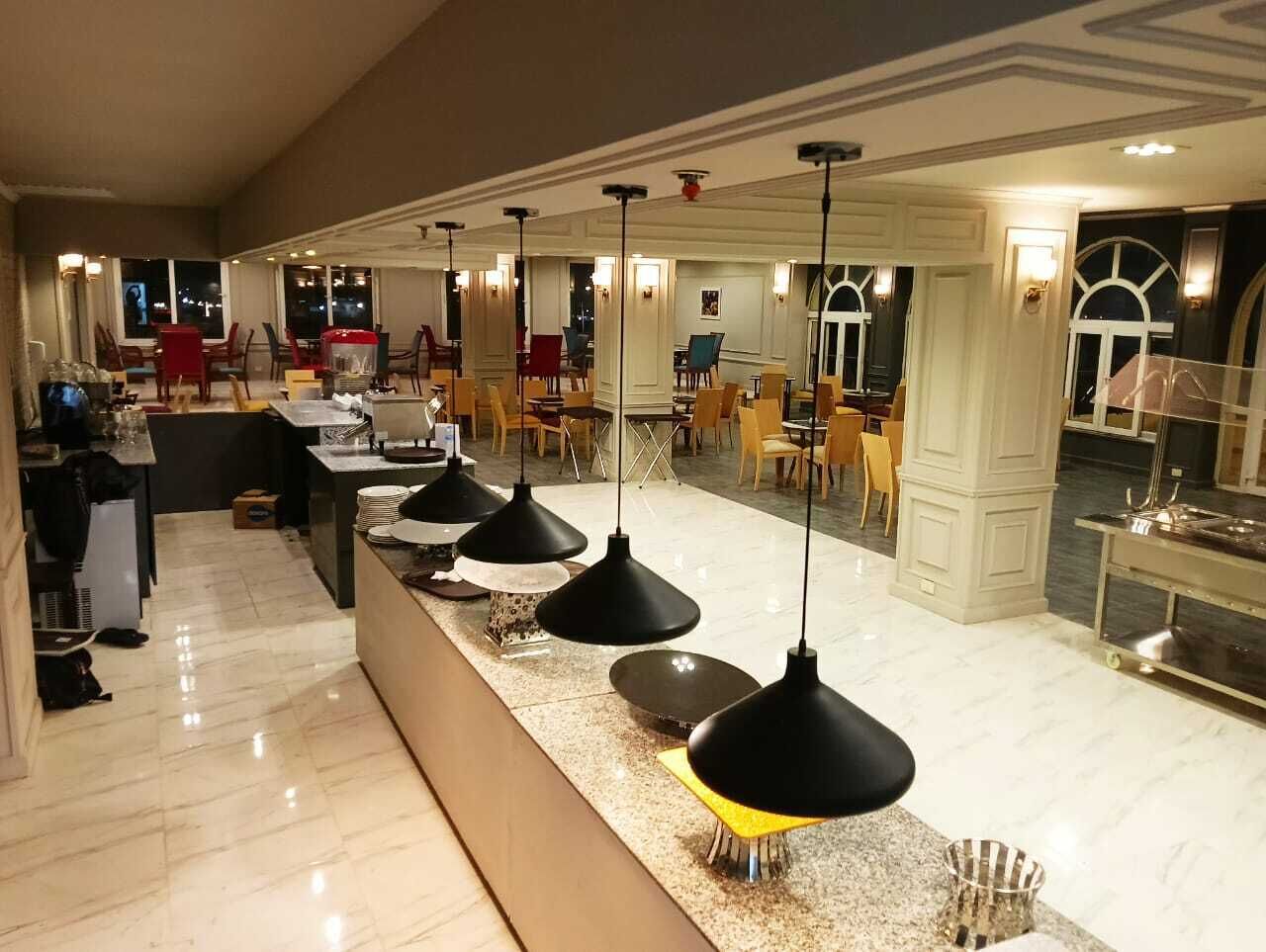 A hotel lobby with a long reception desk, multiple chairs, and pendant lighting.