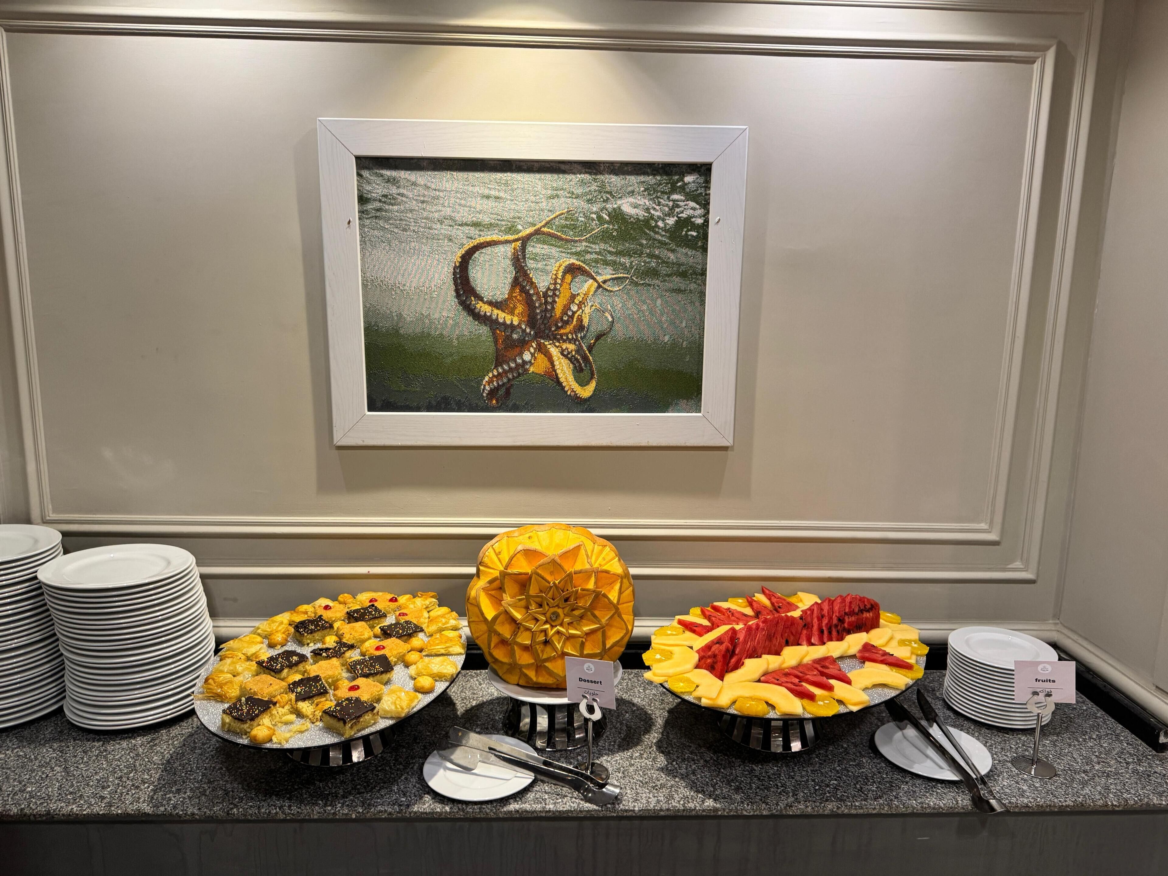 Een buffet met diverse gerechten en een kunstwerk in een lijst aan de muur.