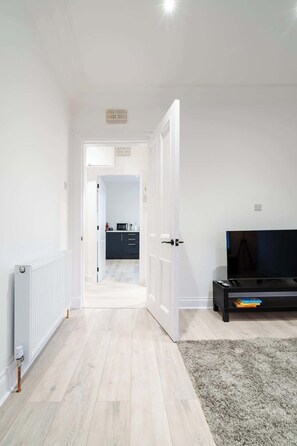 Relax in this stylish living room with a large flat-screen TV, comfortable seating area, and convenient access to the kitchen.