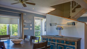 A dining area with a wooden table and chairs, a blue cabinet, and a ceiling fan.