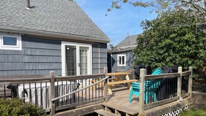 A deck with wooden railings, a picnic table, and a covered area with chairs.