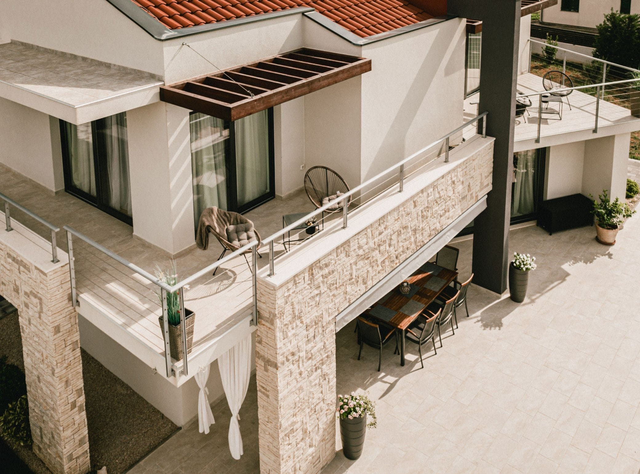 Un bâtiment moderne doté d’un balcon, d’un espace extérieur aménagé et de plantes en pot.