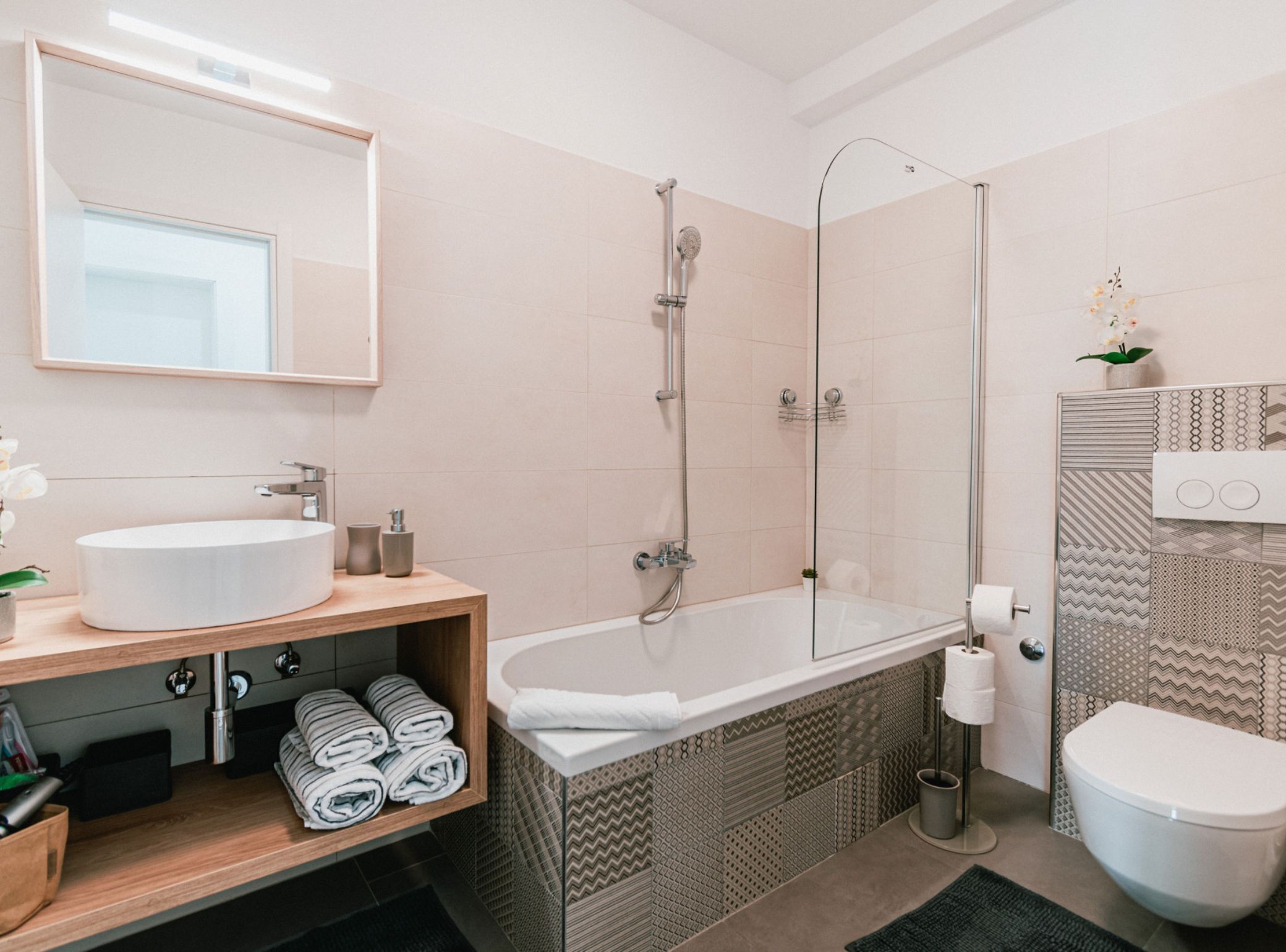 Une salle de bain moderne dotée d’une grande baignoire, d’une douche séparée, de toilettes et d’un lavabo avec un meuble-vasque en bois.