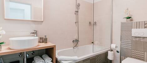 Une salle de bain moderne dotée d’une grande baignoire, d’une douche séparée, de toilettes et d’un lavabo avec un meuble-vasque en bois.