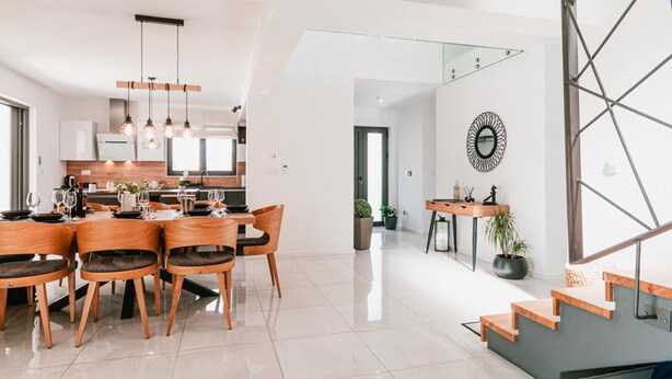 A modern kitchen with white cabinets, a dining area with wooden chairs and a table, and a staircase with a geometric design. - Villa Felicity B4 (Sibenik)