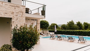 A modern building with a stone facade, a rooftop terrace with a pool, and lounge chairs. - Villa Felicity B4 (Sibenik)
