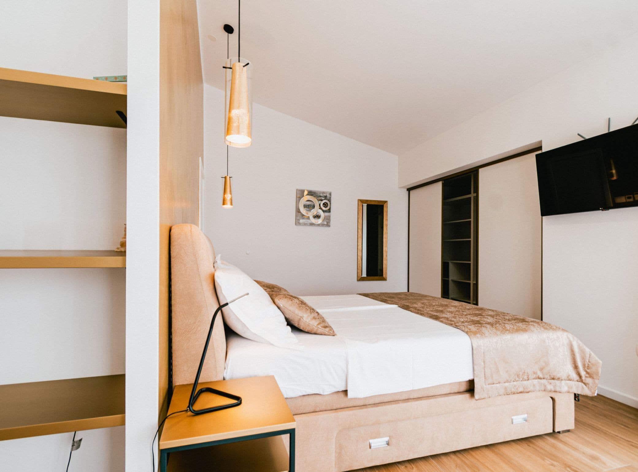 A modern bedroom with a bed, bedside table, and a wardrobe.