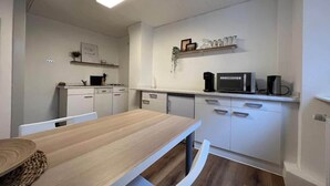 A modern kitchen with white cabinetry, a wooden dining table, and a microwave on the countertop. - Apartment in Vallendar Near Rhine Promenade (Vallendar)