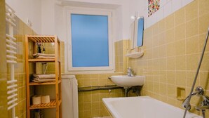 A bathroom with a bathtub, a window, a shelf with towels, and a toilet. - Apartment in Vallendar Near Rhine Promenade (Vallendar)