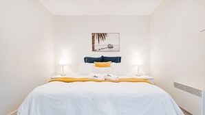 Een hotelkamer met een groot bed, twee bedlampen, een ingelijste foto aan de muur en een radiator.