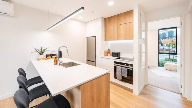Een moderne keuken met een centraal eiland, inbouwapparatuur en uitzicht naar buiten.