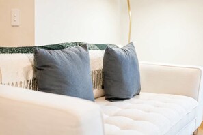 Un canapé blanc avec deux coussins gris et une couverture verte et blanche.