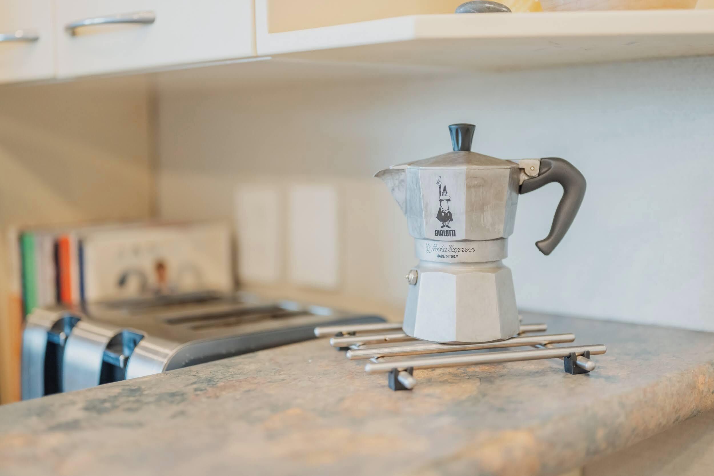 A coffee maker on a kitchen counter with a tray stand.
