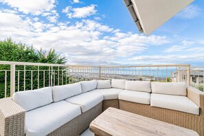 Un balcón con sofá de mimbre y mesa de madera, con vistas a la ciudad.