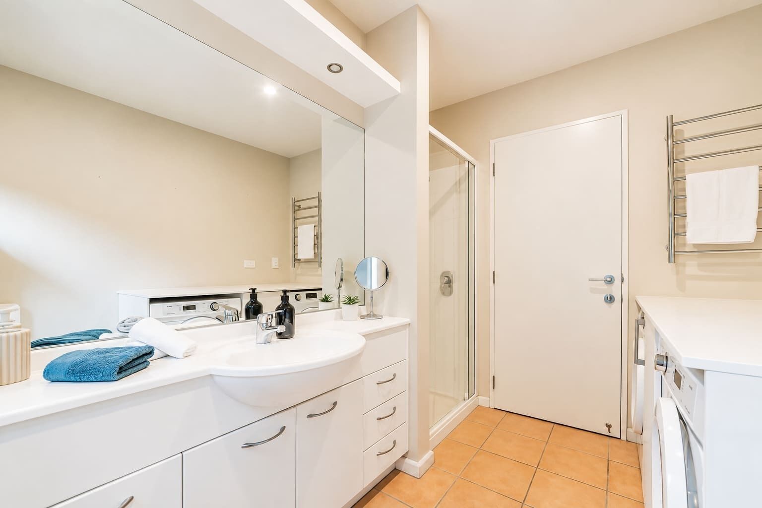 A modern bathroom with a white sink, mirror, and a glass shower enclosure.