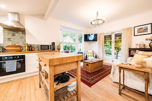 Een moderne keuken met een houten tafel, een televisie en uitzicht op groen.