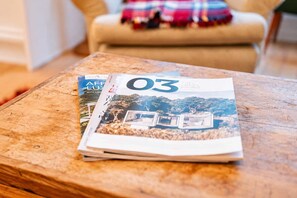 Een tijdschrift op een houten tafel, met uitzicht op een huis en bomen.