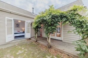 Ein gemütliches Cottage mit einer Holzterrasse, einer Veranda und einem kleinen Garten.