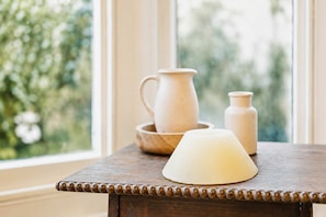 Een houten tafel met een kaars, een karaf en een kleine vaas.