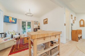 Ein gemütliches Wohnzimmer mit Couch, Holz-Couchtisch, rotem Teppich mit Muster und Bücherregal.