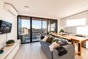 A modern apartment with a balcony, a dining area, and a living room with a sofa.