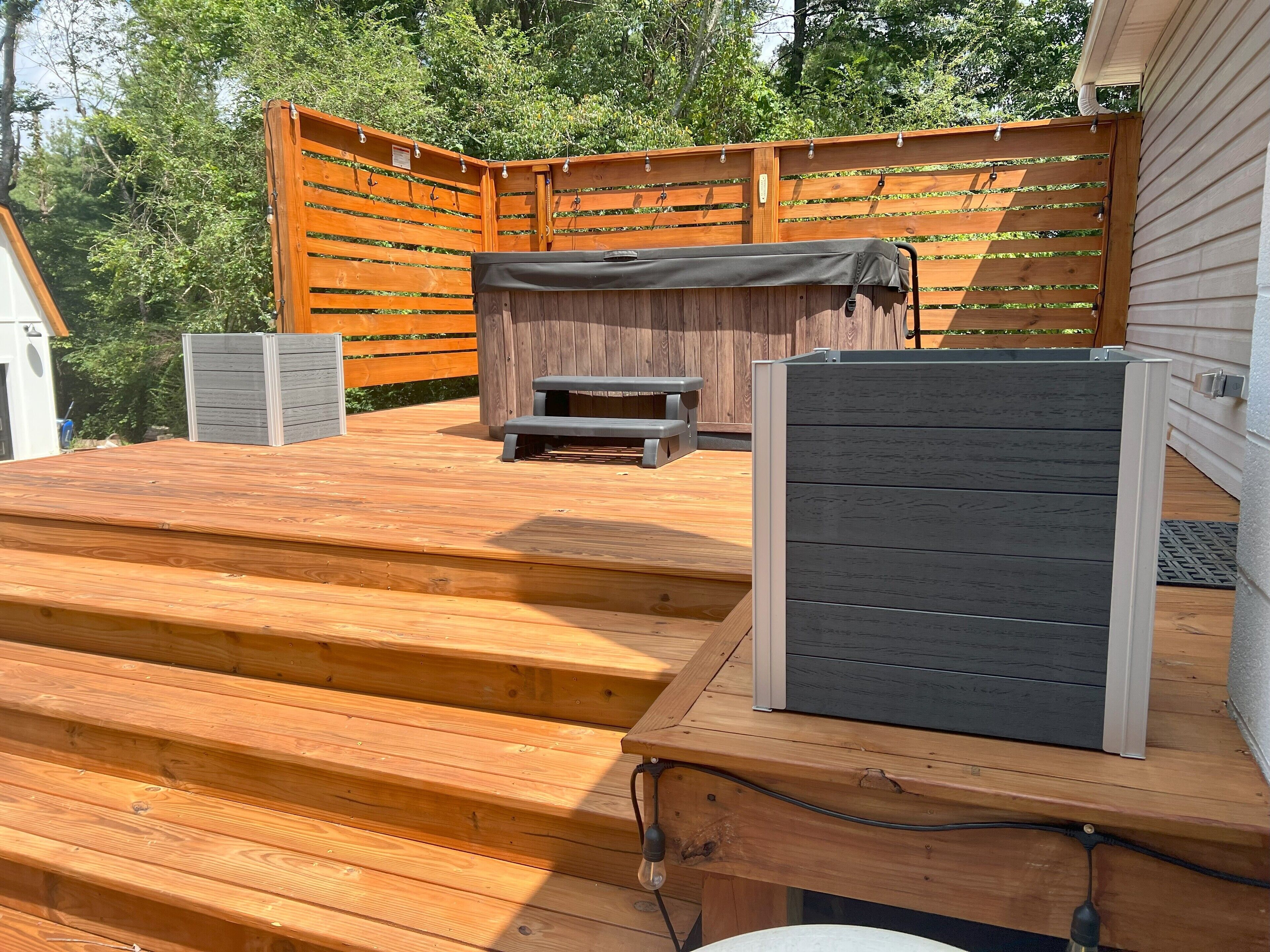 Une terrasse en bois avec un espace salon couvert, une petite table et un barbecue.