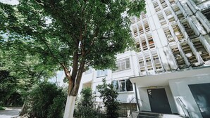 Un immeuble résidentiel à plusieurs étages, avec un escalier menant à l’entrée.