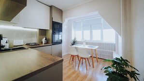 Une cuisine moderne avec un coin repas, un plancher en bois et une grande fenêtre qui laisse entrer la lumière naturelle.
