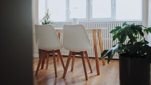 Un coin repas avec une table en bois et deux chaises blanches.