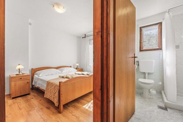 A bedroom with a wooden bed, a nightstand, a bedside lamp, and a window with curtains.