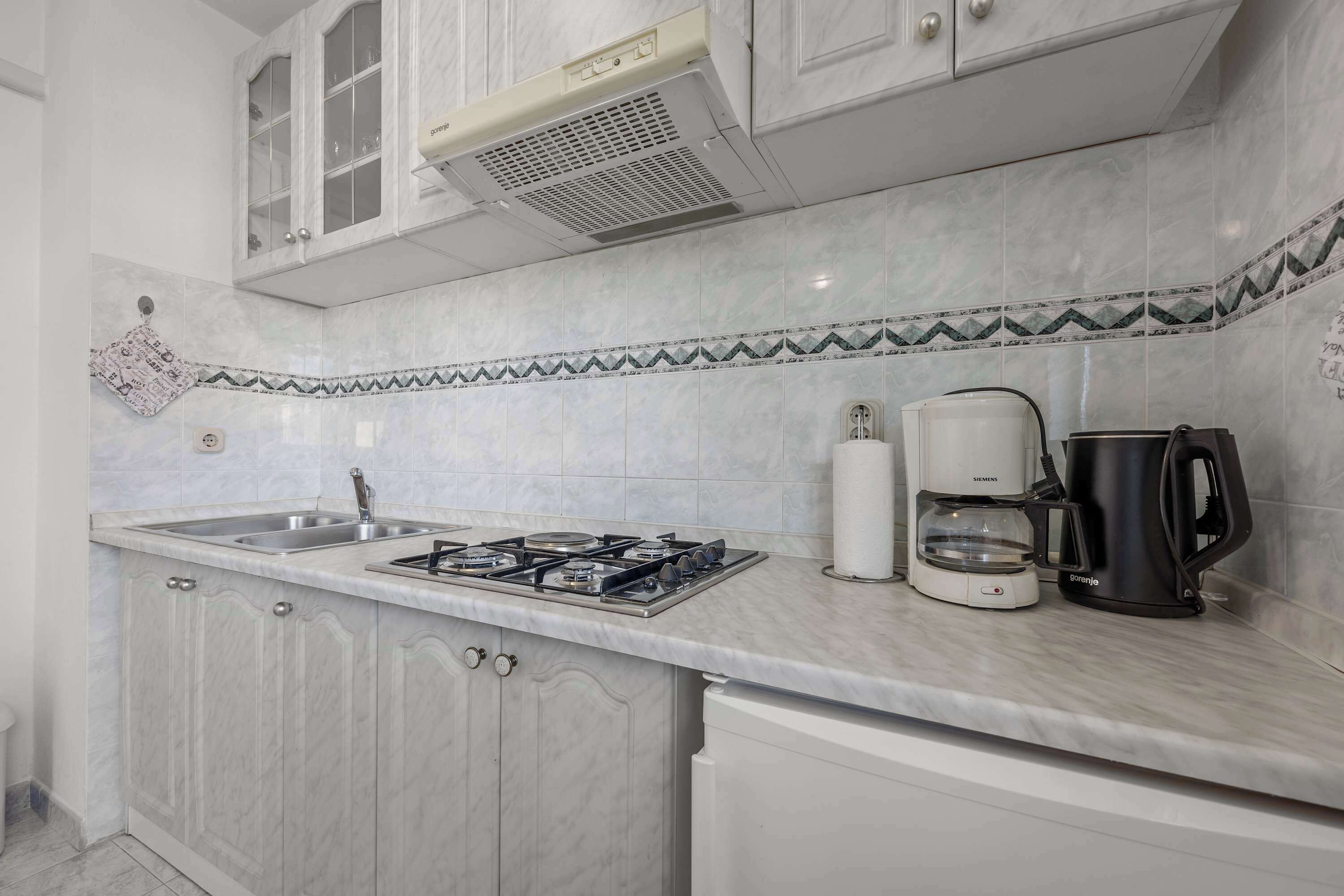A kitchen with a gas stove, a coffee maker, and a kettle.