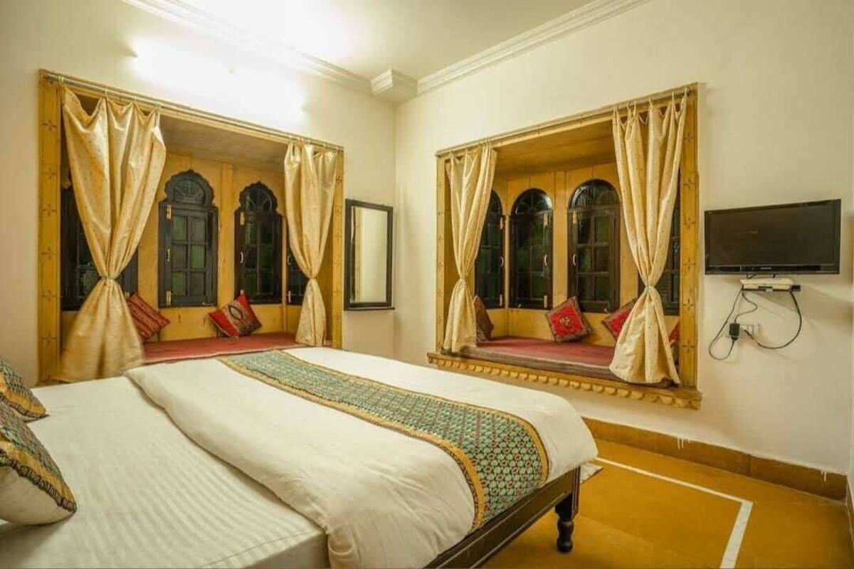 A hotel room with two beds, each with a canopy, a television, and a large mirror.