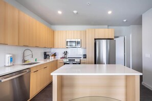 Enjoy cooking in this well-equipped kitchen with a central island, sink, and stainless steel appliances.