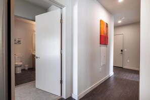Stylish hallway leads to a bathroom with a toilet and trash bin.