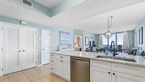 A modern kitchen with white cabinetry, a dishwasher, and a large island with a sink. - Sandy shores await! Book this 3/3 Sleeping 7 NOW! (Navarre)