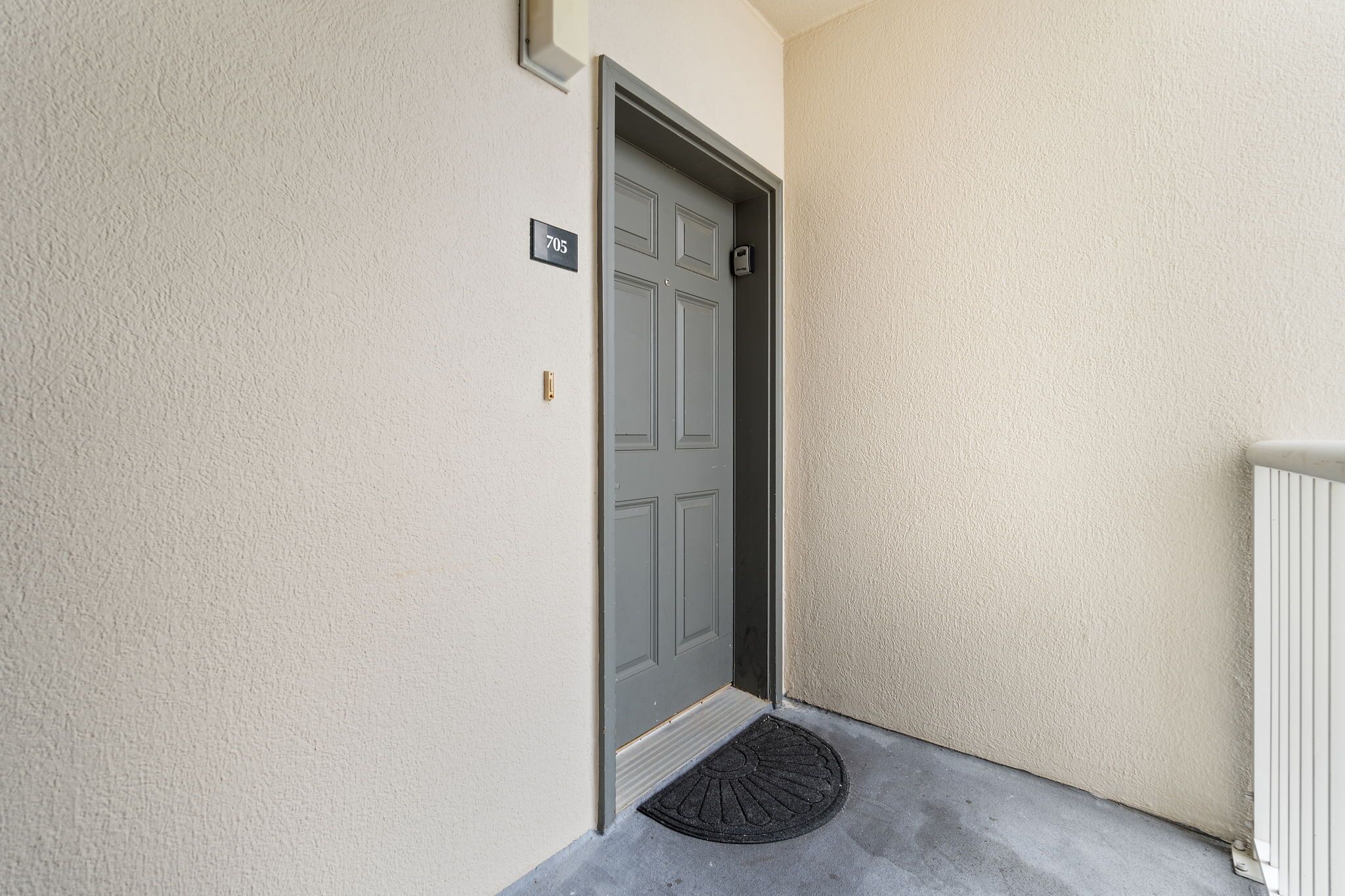 A door with a number plate, a doormat, and a radiator.