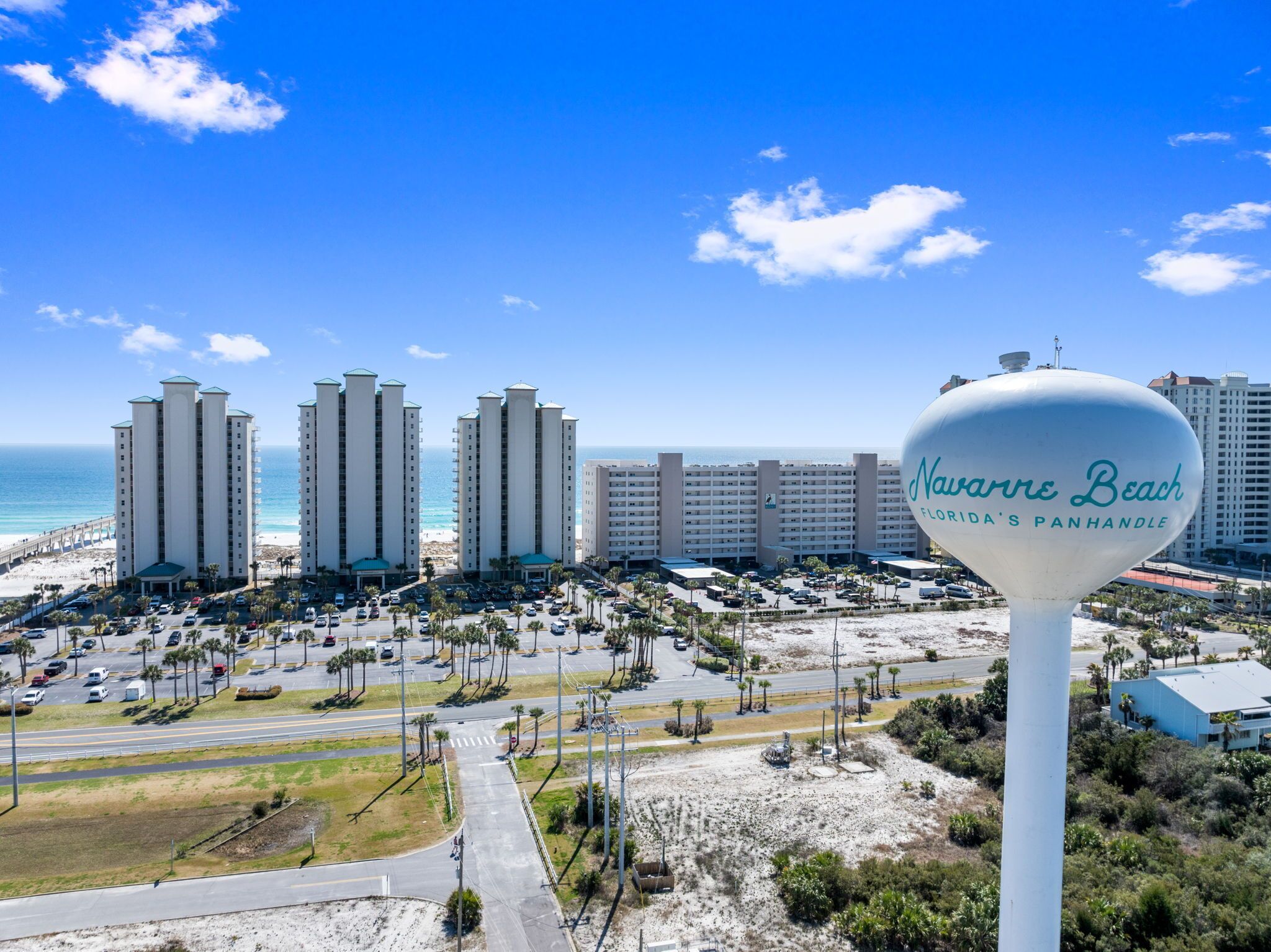 A view of a beachside hotel with a large sign reading "Navasero Beach Florida's Panhandle".