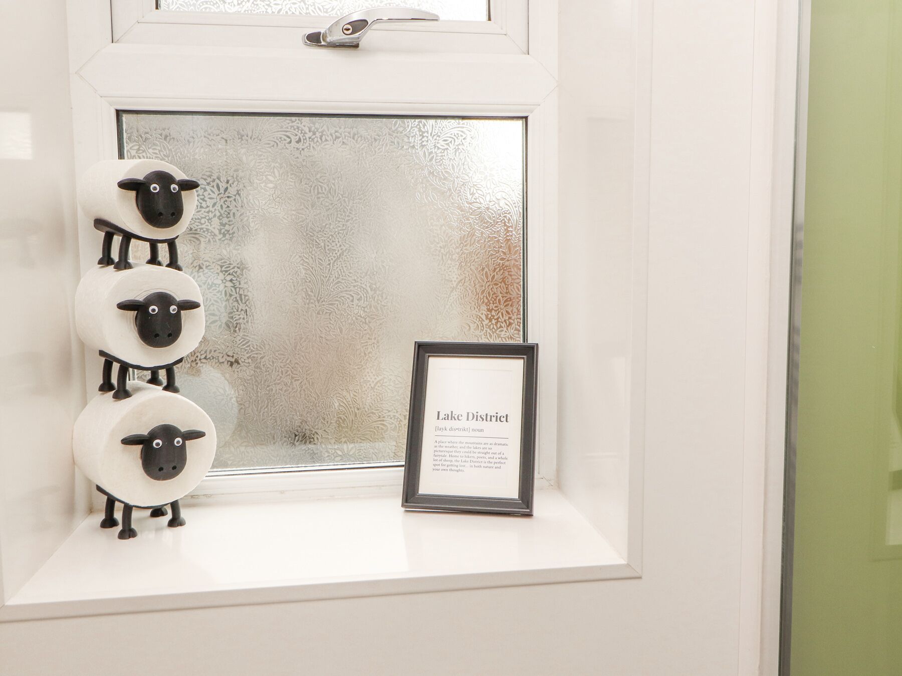 A window with a decorative sheep sculpture and a framed text about Lake District.