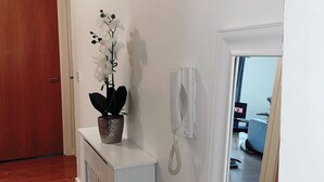 A hallway with a white radiator, a potted orchid, and a wall-mounted telephone.
