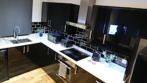 Una cocina moderna con armarios negros, encimera blanca y electrodomésticos de acero inoxidable.