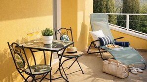 A balcony with a table, chairs, a sun lounger, and a view of trees. - La Gialla (Attico d'Amore) By Case al Lago (Padenghe sul Garda)