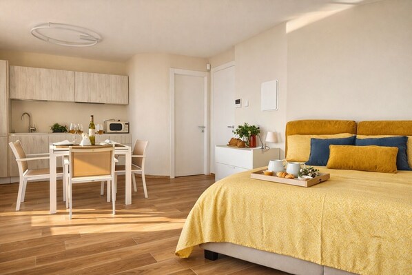 A modern bedroom with a bed, bedside table, and a small sitting area with a table and chairs. - La Gialla (Attico d'Amore) By Case al Lago (Padenghe sul Garda)