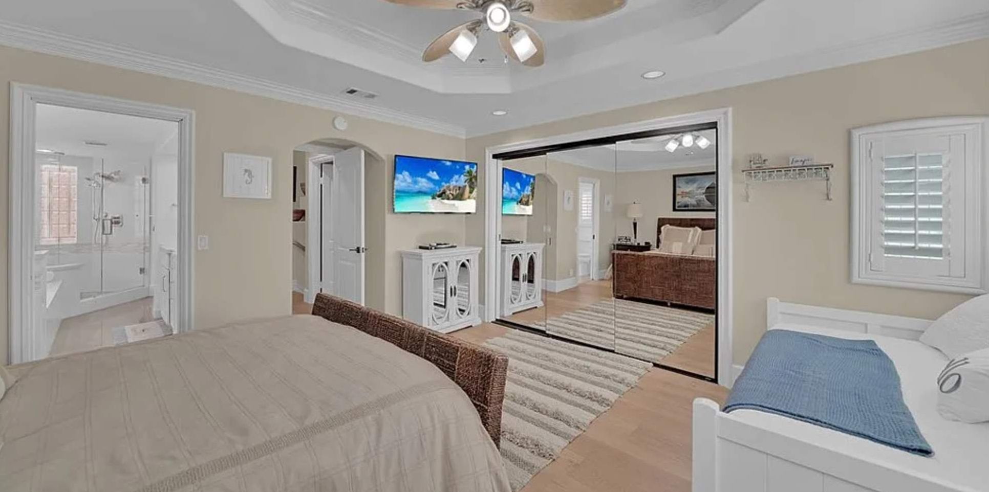 A bedroom with a bed, a television, a wardrobe, and a bathroom visible through an open door.