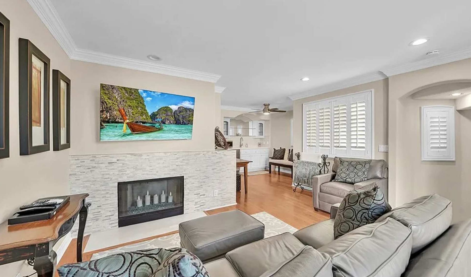A living room with a fireplace, a sofa, and a dining area in the background.